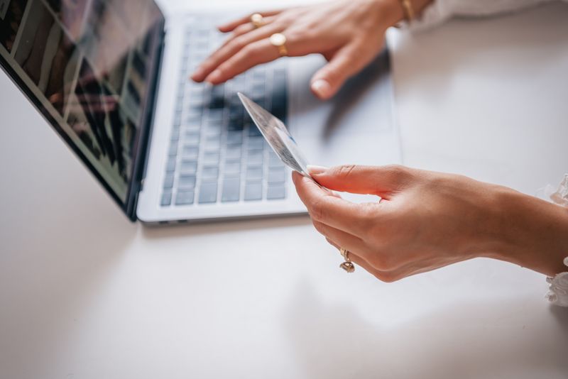 Manos con una tarjeta frente a una notebook, comprando por internet