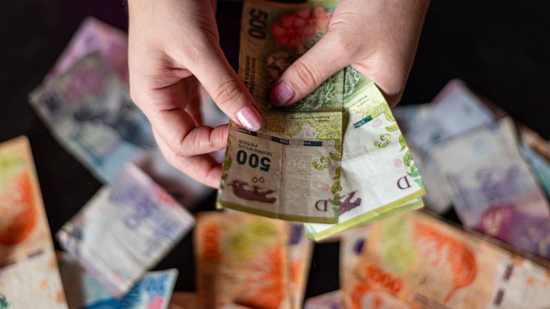 Manos contando billetes de pesos argentinos