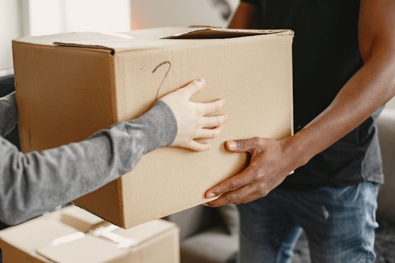 Una persona le entrega una caja de cartón a otra